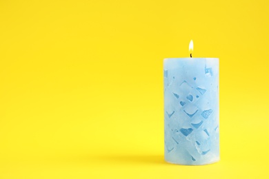 Alight wax candle on color background. Space for text