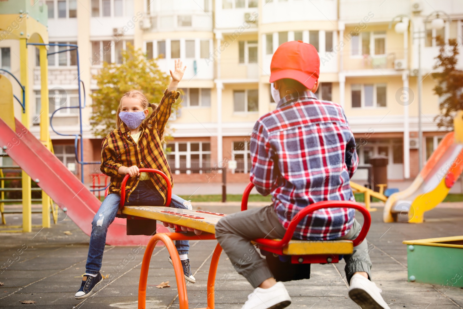 Photo of Little children with medical face masks on playground during covid-19 quarantine