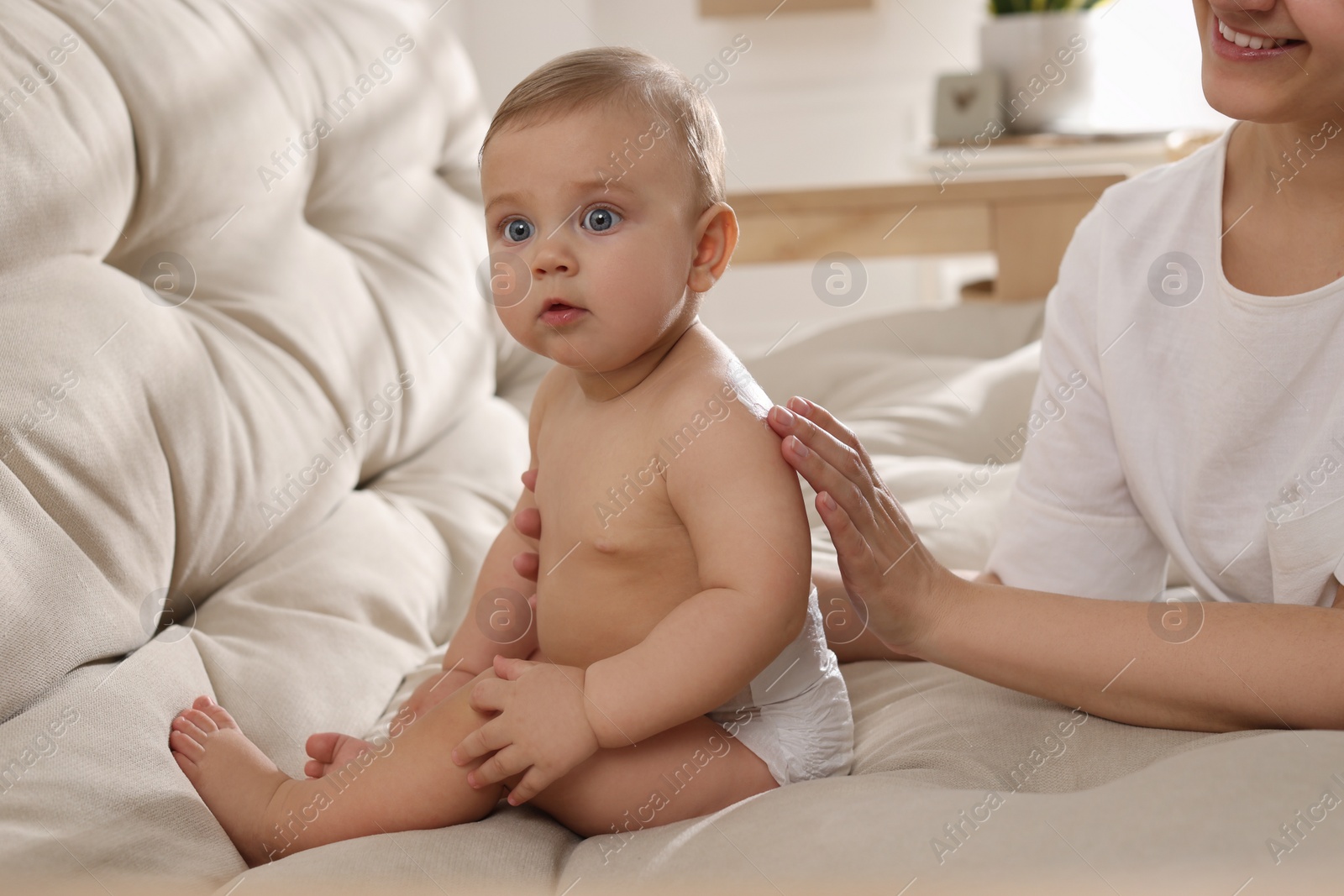 Photo of Mother applying body cream on her little baby at home, closeup