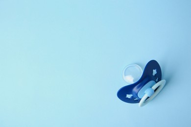 Photo of One baby pacifier on light blue background, top view. Space for text