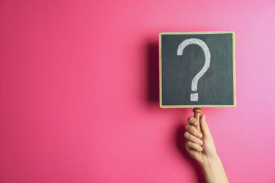 Photo of Woman holding blackboard with question mark on pink background, closeup. Space for text