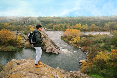 Man with travel backpack enjoying nature near mountain river