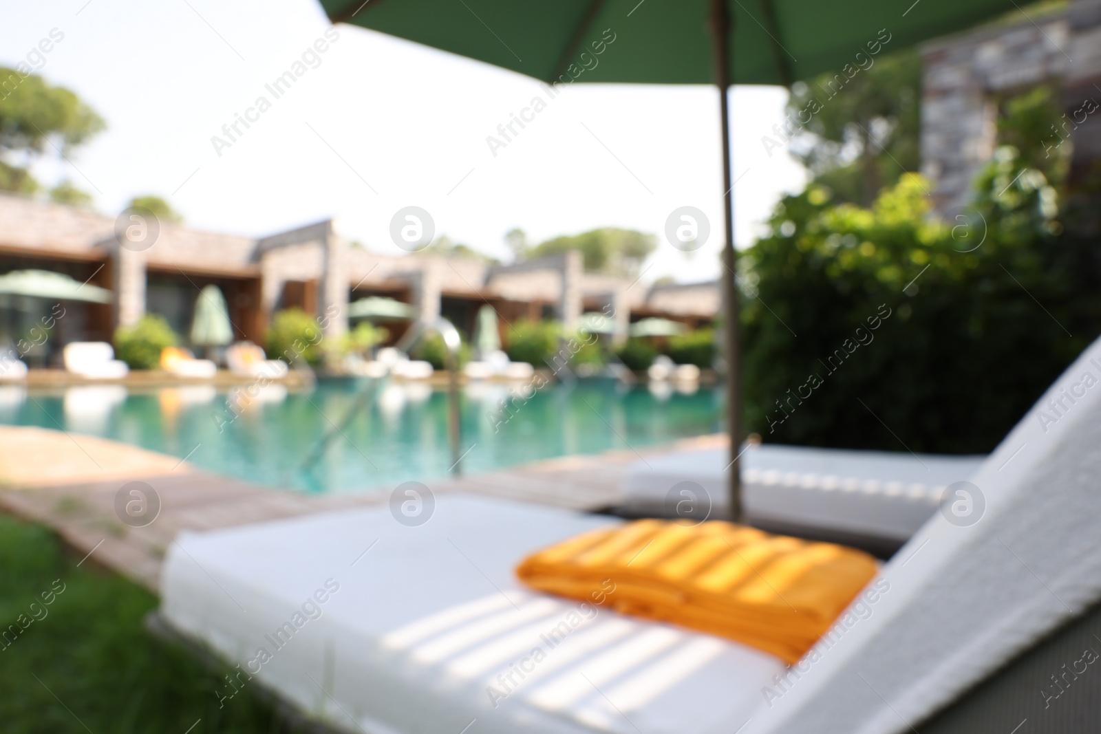 Photo of Sunbeds near swimming pool at luxury resort, blurred view