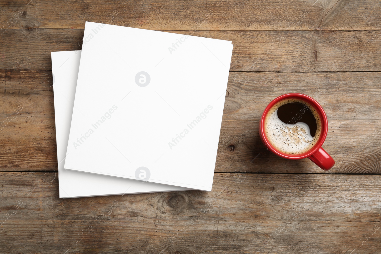 Photo of Blank paper sheets for brochure and cup of coffee on wooden background, flat lay. Mock up