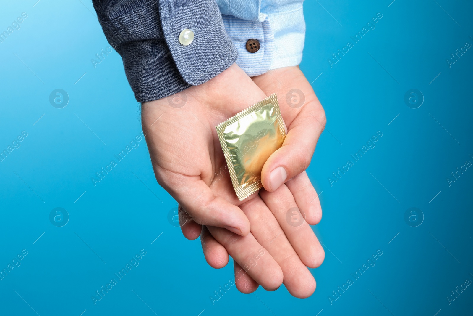 Photo of Gay couple with condom on light blue background, closeup