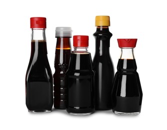 Photo of Bottles of tasty soy sauce isolated on white