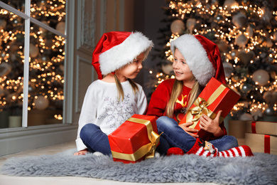 Cute little children with Christmas gifts at home