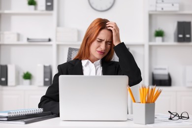 Photo of Woman suffering from headache at workplace in office