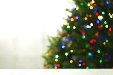 Photo of Empty table and blurred fir tree with colorful Christmas lights on background, bokeh effect. Space for design