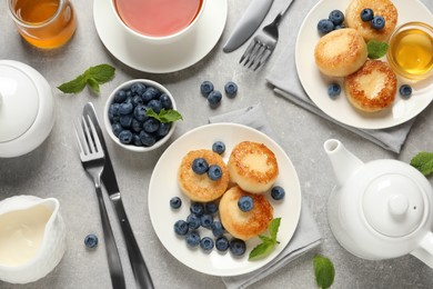 Photo of Delicious cottage cheese pancakes with blueberries, mint and honey served on light grey table, flat lay