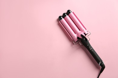 Photo of Modern triple curling hair iron on pink background, top view. Space for text