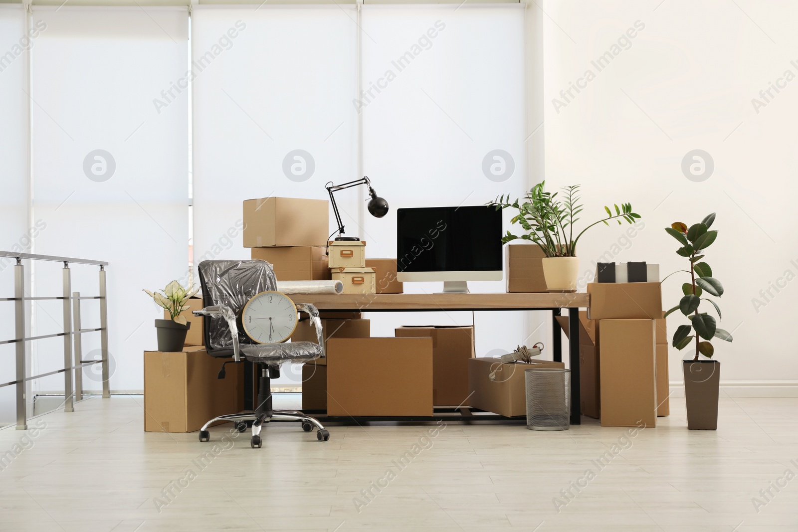 Photo of Cardboard boxes, computer and furniture in new office. Moving day