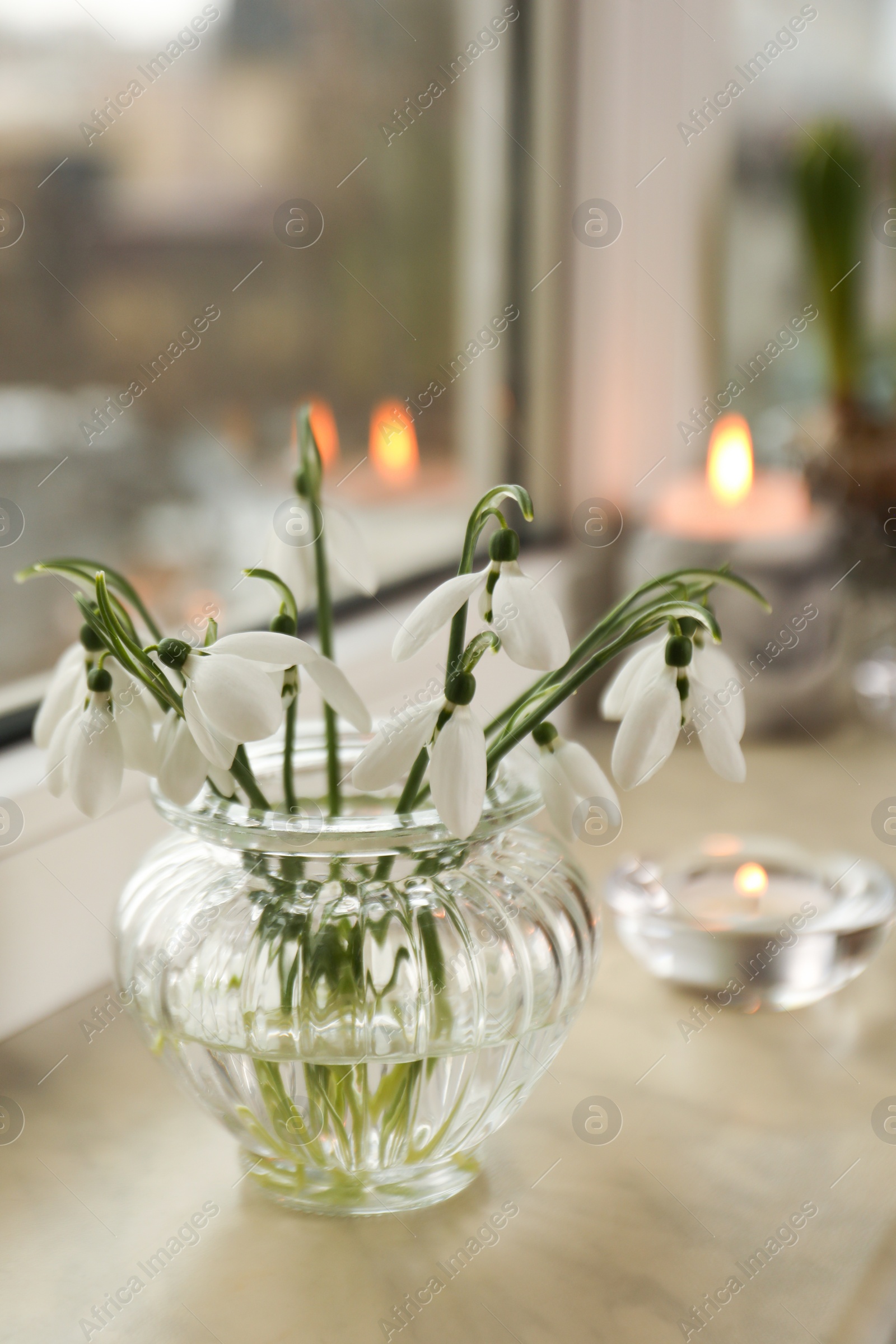 Photo of Spring is coming. Beautiful snowdrops and candle on windowsill indoors