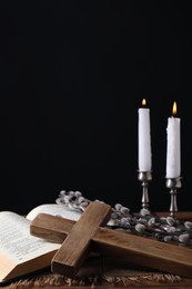 Burning church candles, cross, Bible and willow branches on table