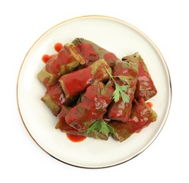 Photo of Delicious stuffed grape leaves with tomato sauce on white background, top view
