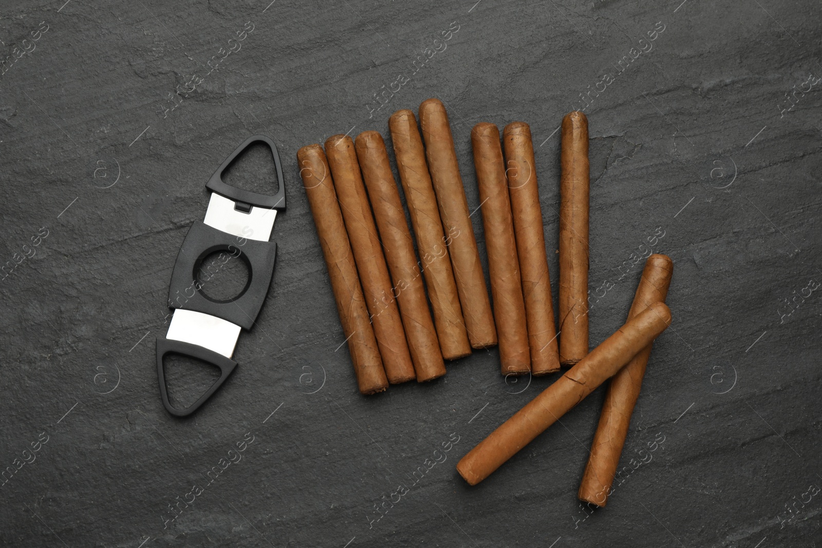 Photo of Cigars and guillotine cutter on black table, flat lay