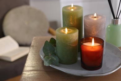 Beautiful burning candles and air freshener on wooden table indoors, space for text