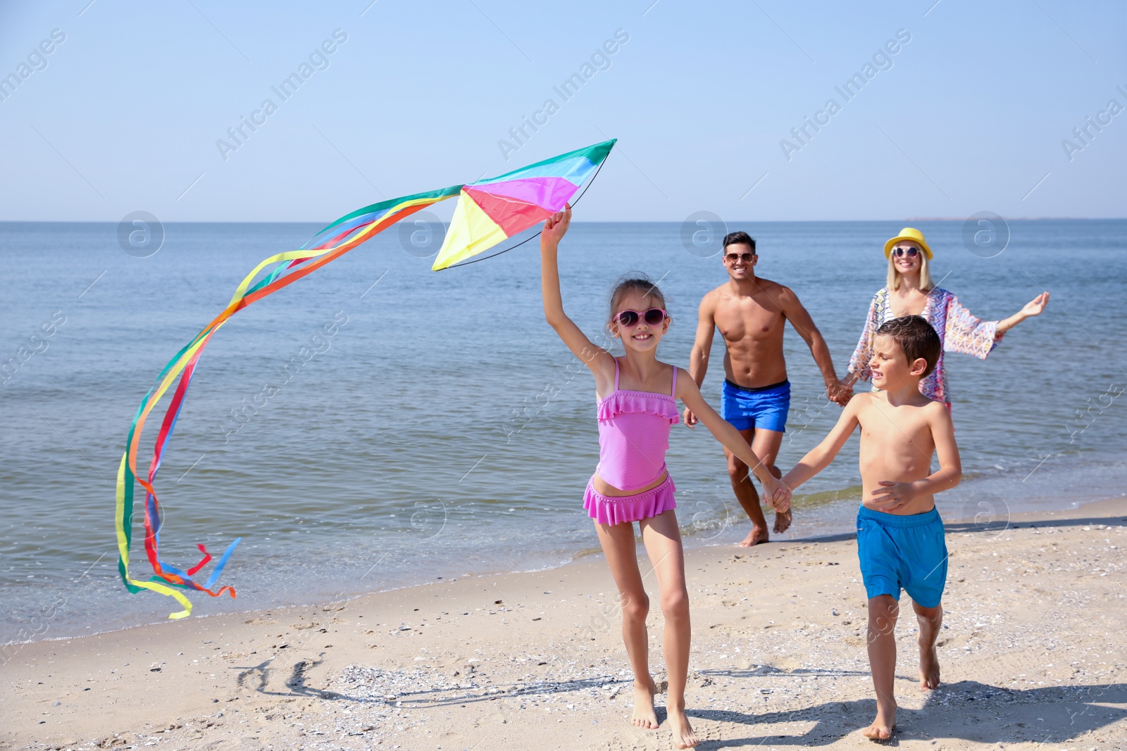 Photo of Happy family with kite at beach on sunny day