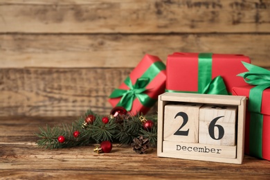 Photo of Block calendar with Boxing Day date near gifts on wooden table. Space for text