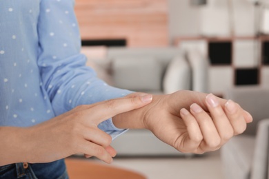 Photo of Young woman checking pulse indoors, closeup. Space for text