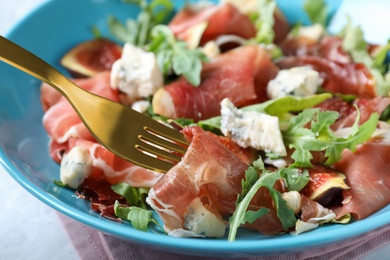 Photo of Salad with ripe figs and prosciutto served in bowl, closeup