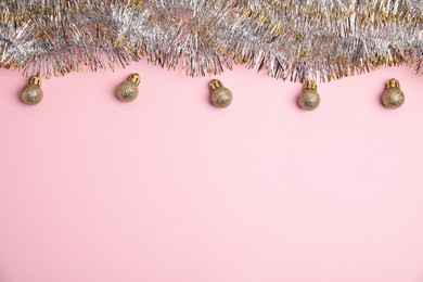 Sparkling tinsel and Christmas balls on pink background, flat lay. Space for text