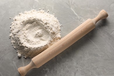 Pile of flour and rolling pin on grey marble table, top view