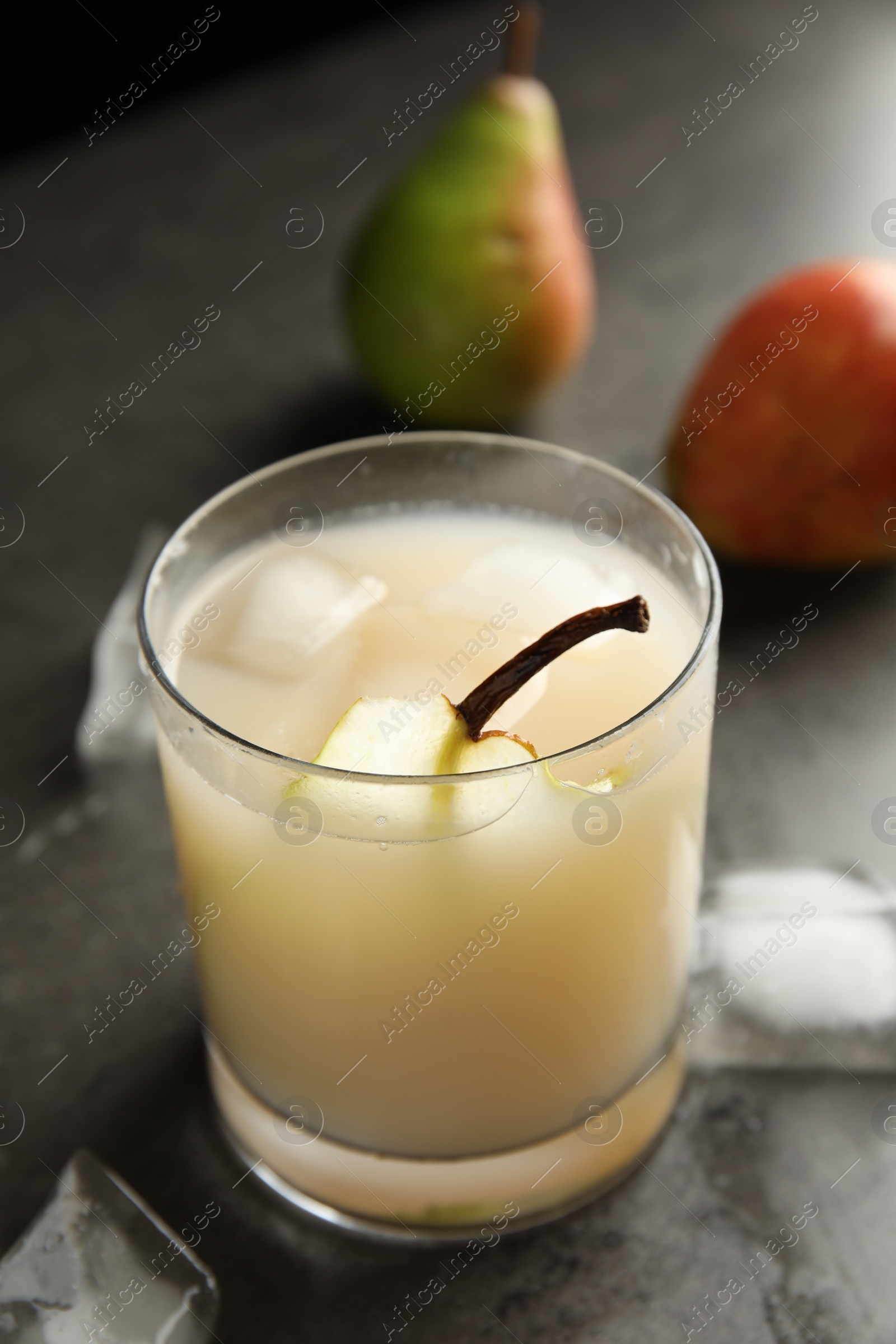 Photo of Fresh juice with pear and ice cubes on grey table, closeup