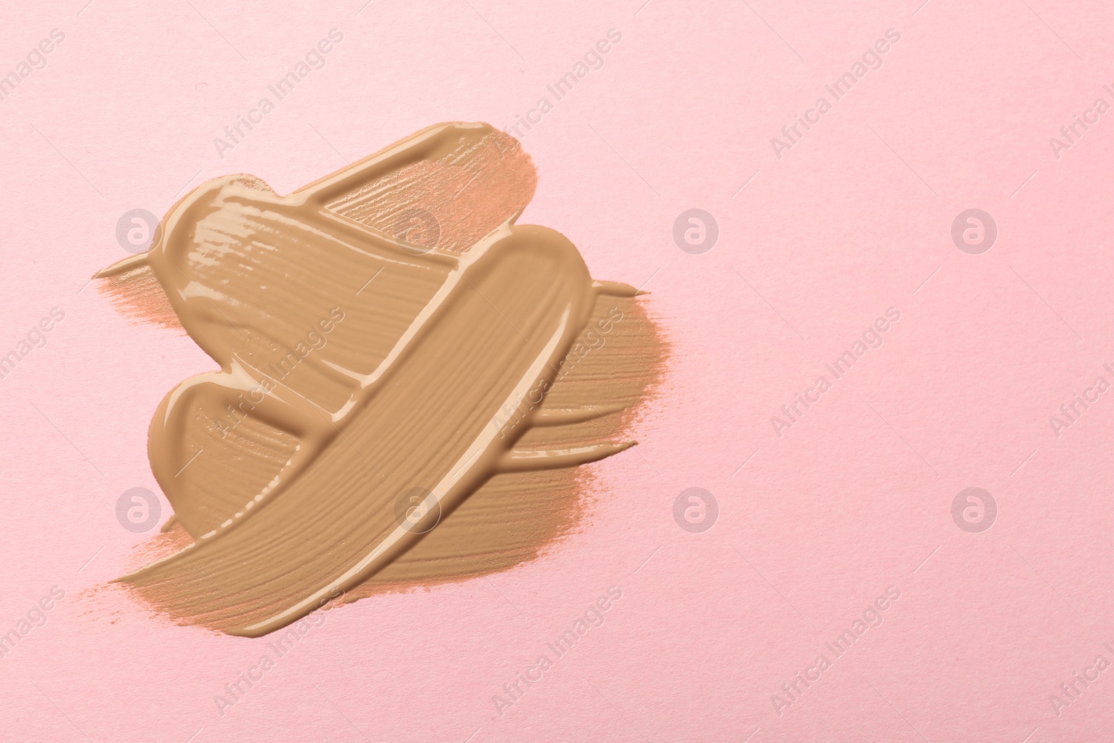 Photo of Sample of liquid skin foundation on pink background, top view. Space for text