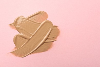 Photo of Sample of liquid skin foundation on pink background, top view. Space for text