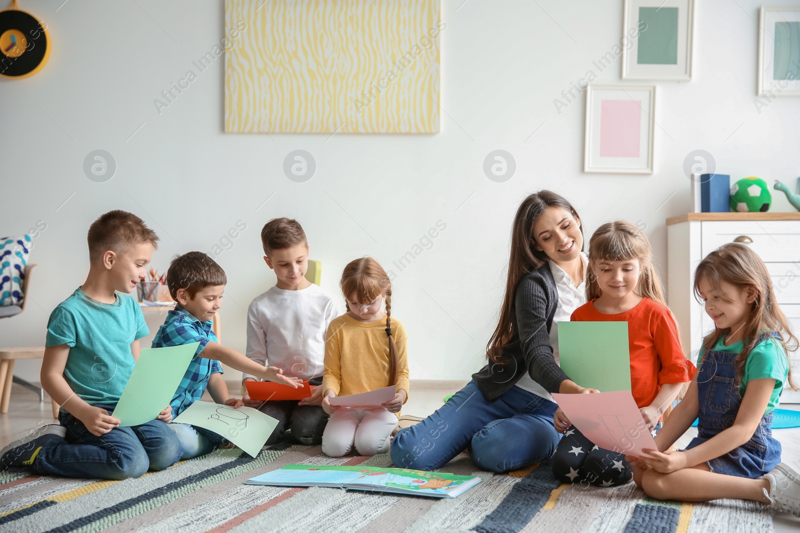 Photo of Cute little children with teacher in classroom at school