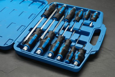 Set of screwdrivers in open toolbox on dark textured table, closeup