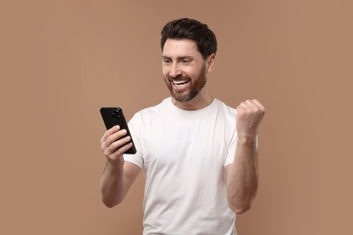 Photo of Happy man with smartphone on light brown background