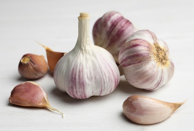 Photo of Fresh organic garlic on white wooden table, closeup