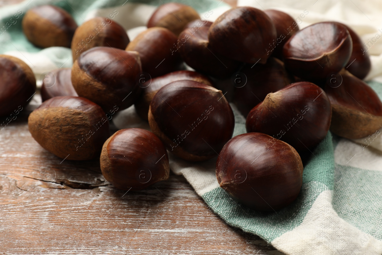 Photo of Sweet fresh edible chestnuts on wooden table, closeup