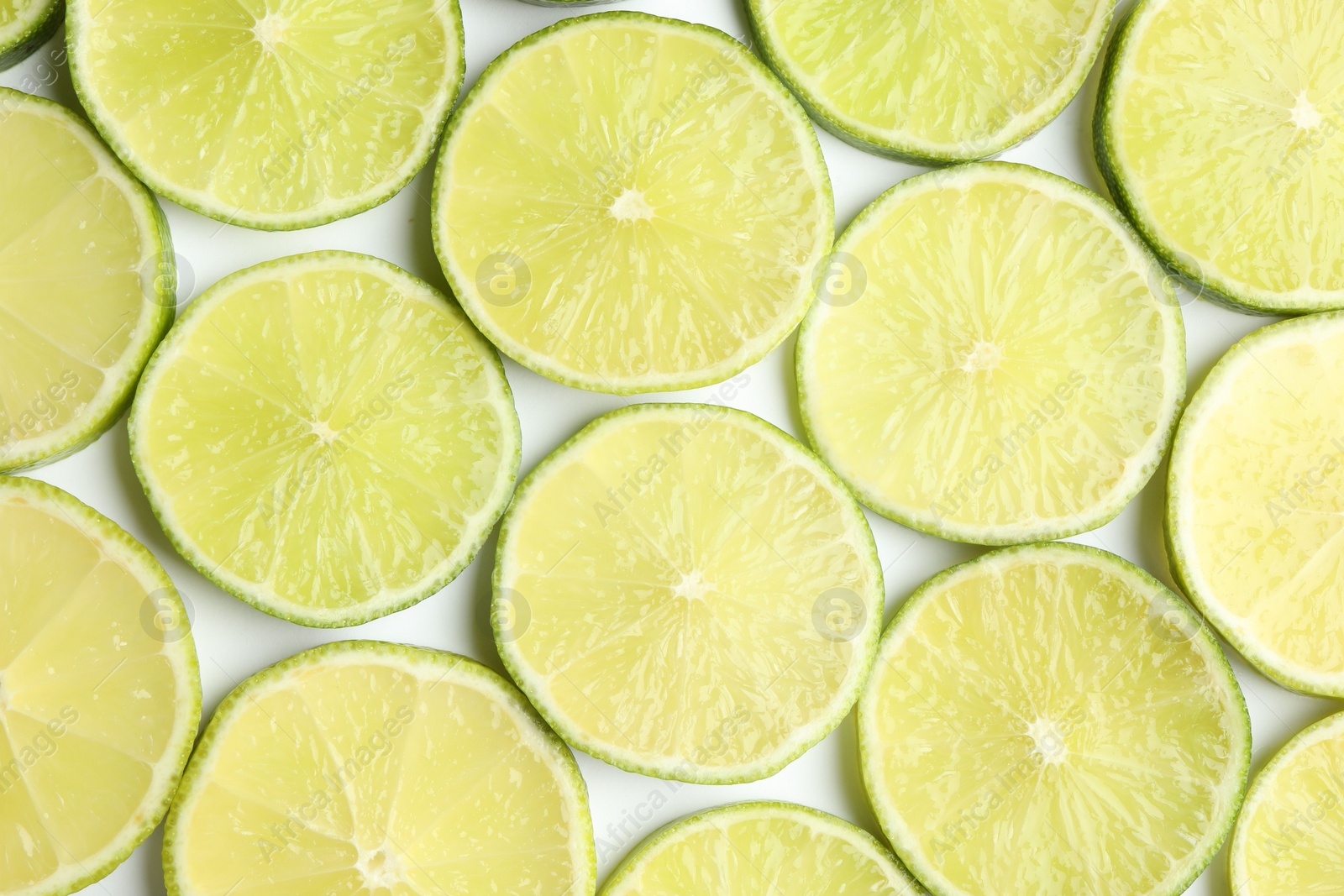 Photo of Fresh juicy lime slices on white background, flat lay