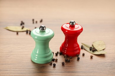 Salt and pepper shakers with bay leaves on wooden table, closeup. Spice mill