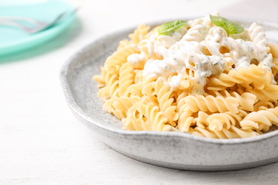 Tasty pasta with sauce and basil on white wooden table, closeup