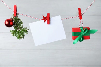 Blank Christmas card and festive decor on rope against white background, space for text