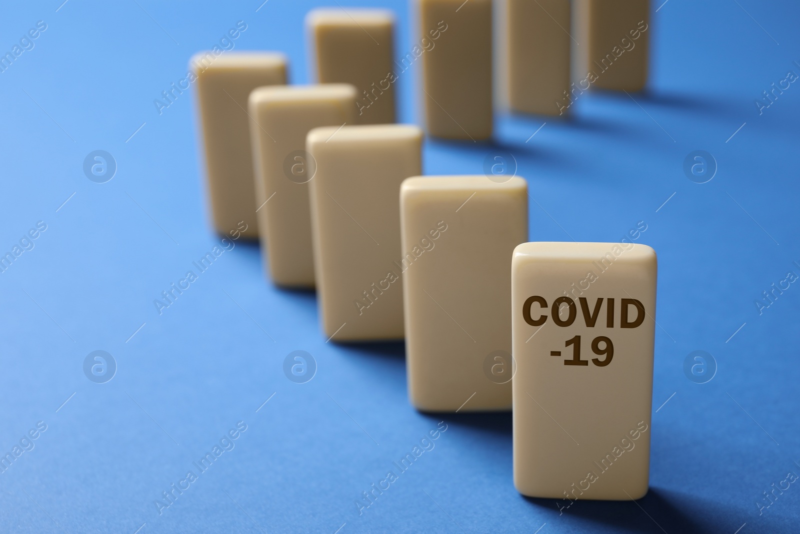 Photo of Domino tiles on blue background, space for text. Spreading of coronavirus concept