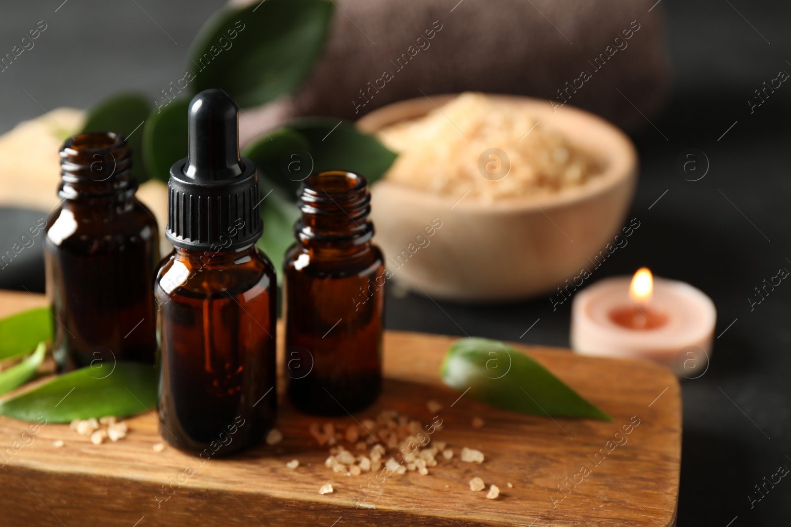 Photo of Composition with aroma oil bottles on wooden board, closeup