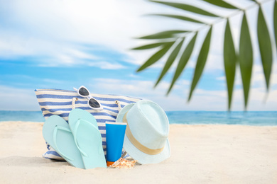 Different stylish beach objects on sand near sea