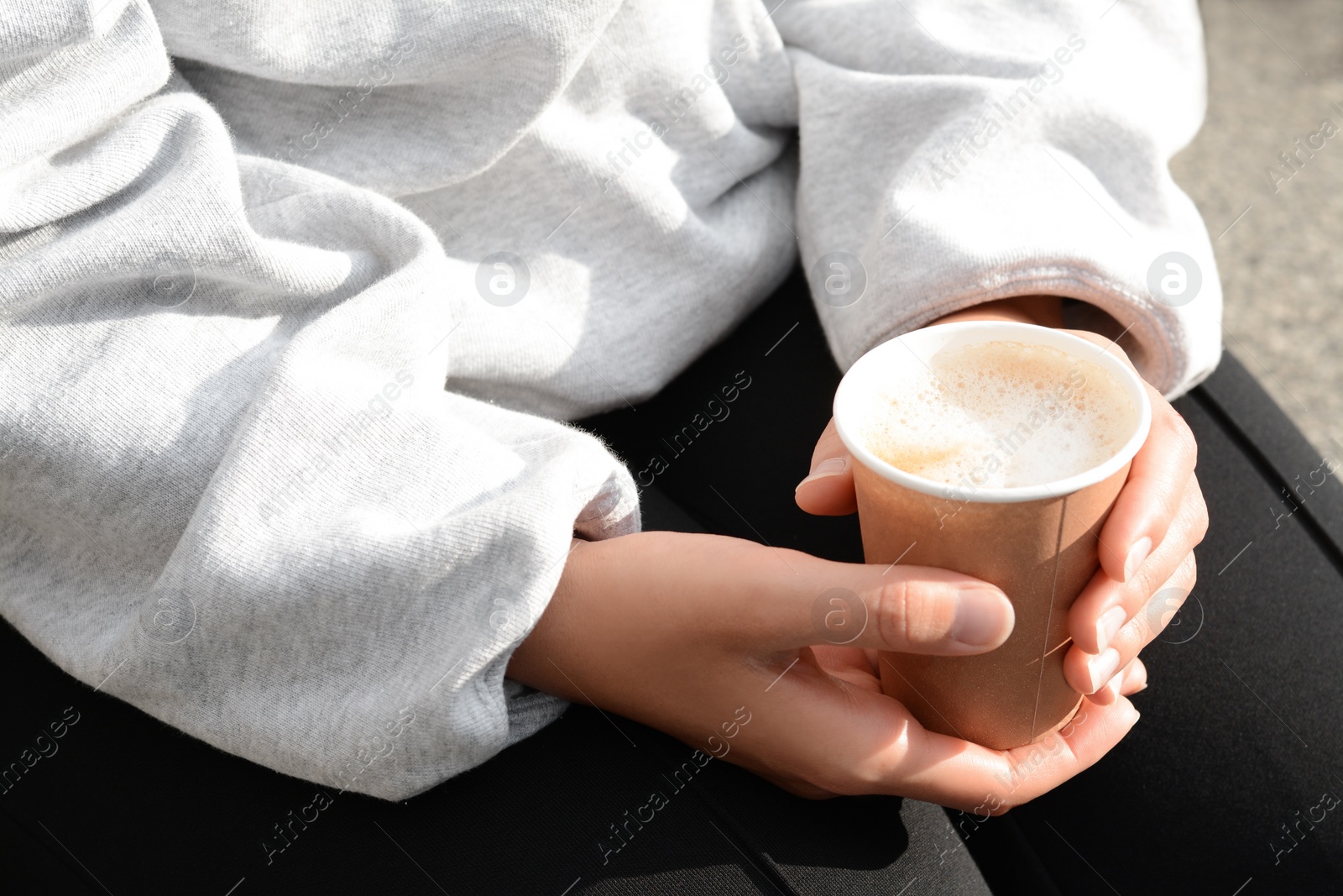 Photo of Woman sitting with cardboard cup of coffee, closeup