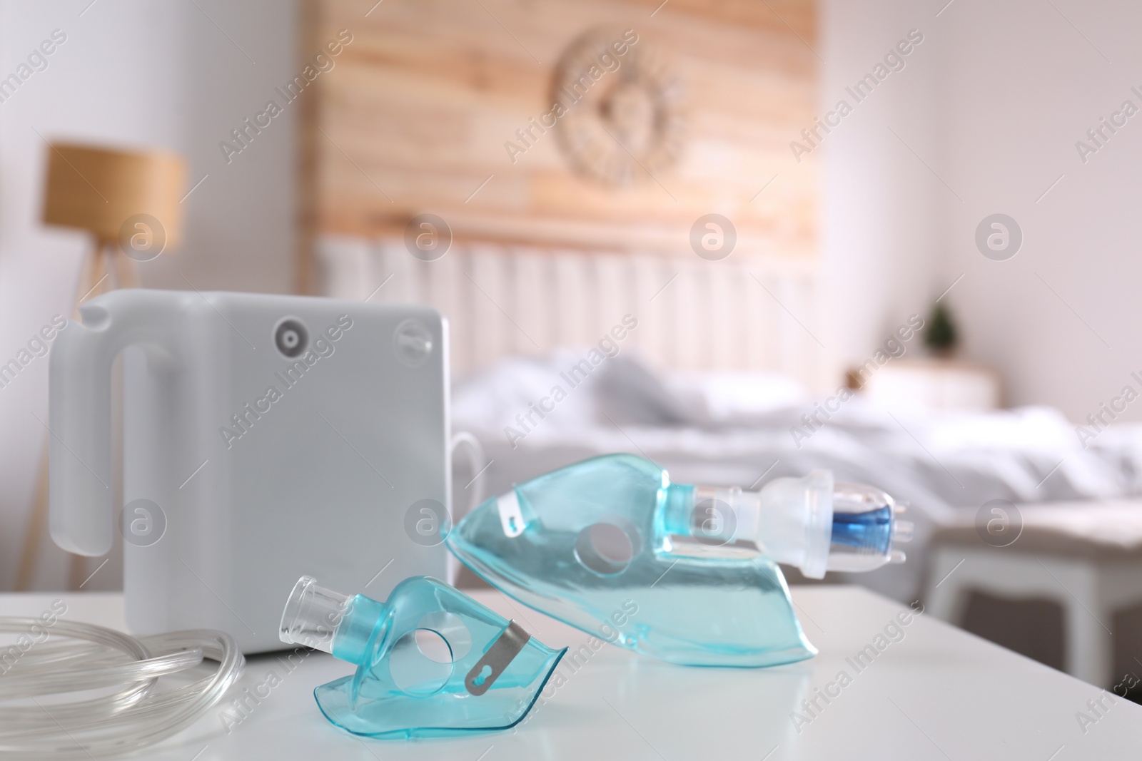 Photo of Modern nebulizer with face masks on white table indoors, space for text. Inhalation equipment