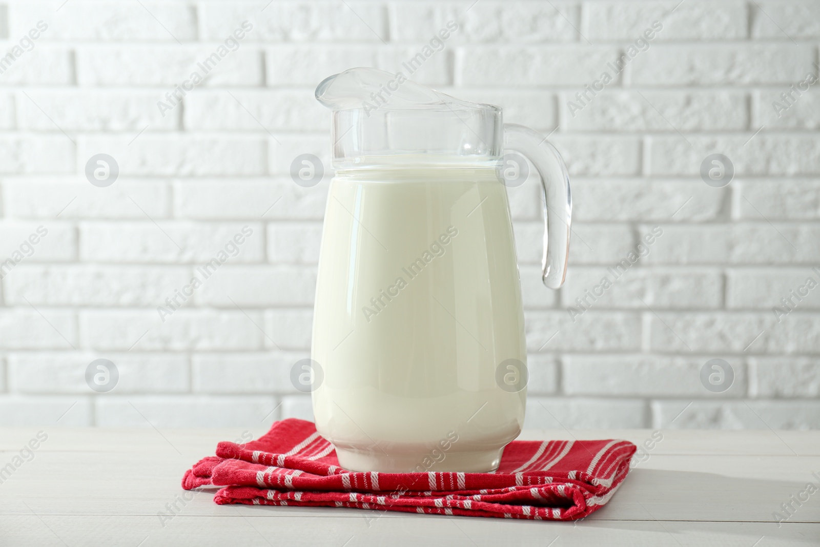 Photo of Jug of fresh milk on white wooden table