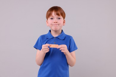 Photo of Little boy with sticking tape on light grey background