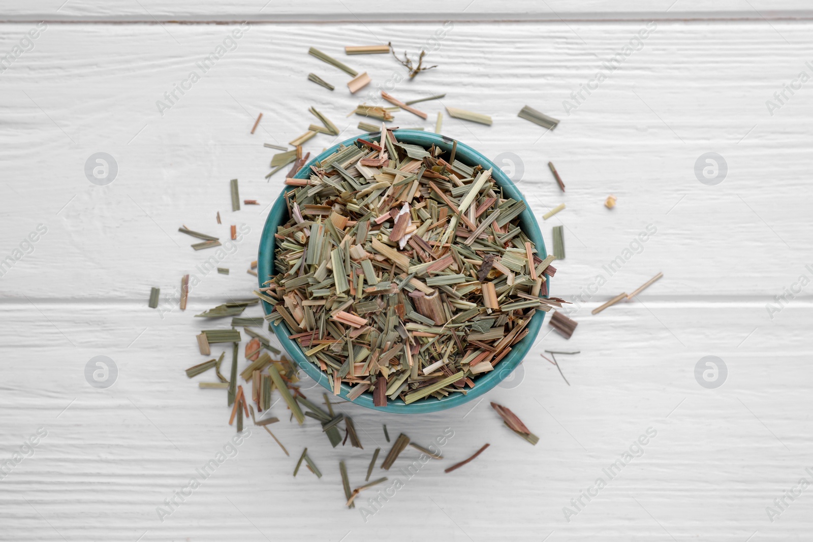 Photo of Bowl with aromatic dried lemongrass on white wooden table, flat lay