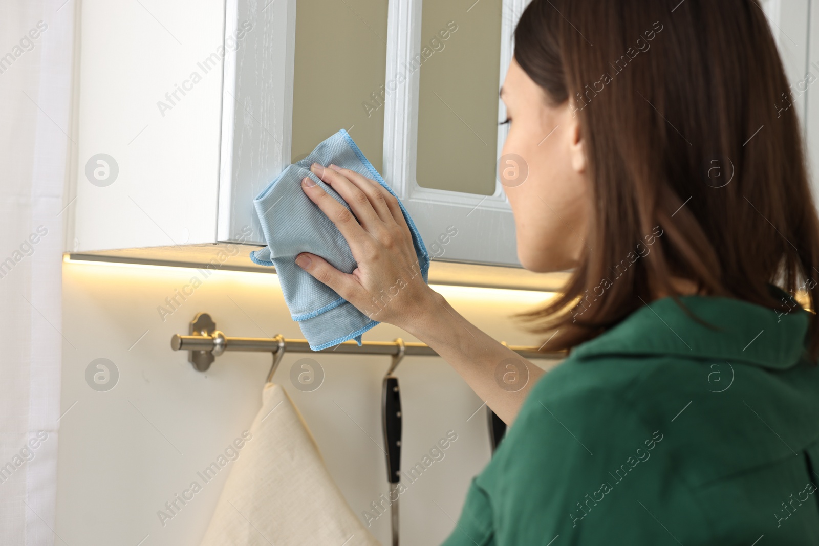 Photo of Woman cleaning furniture with rag in kitchen, selective focus