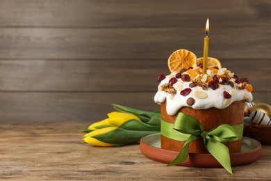 Photo of Tasty Easter cake with dried fruits, flowers and decorated eggs on wooden table. Space for text