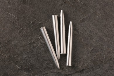 Photo of Metal bullets on dark textured table, flat lay